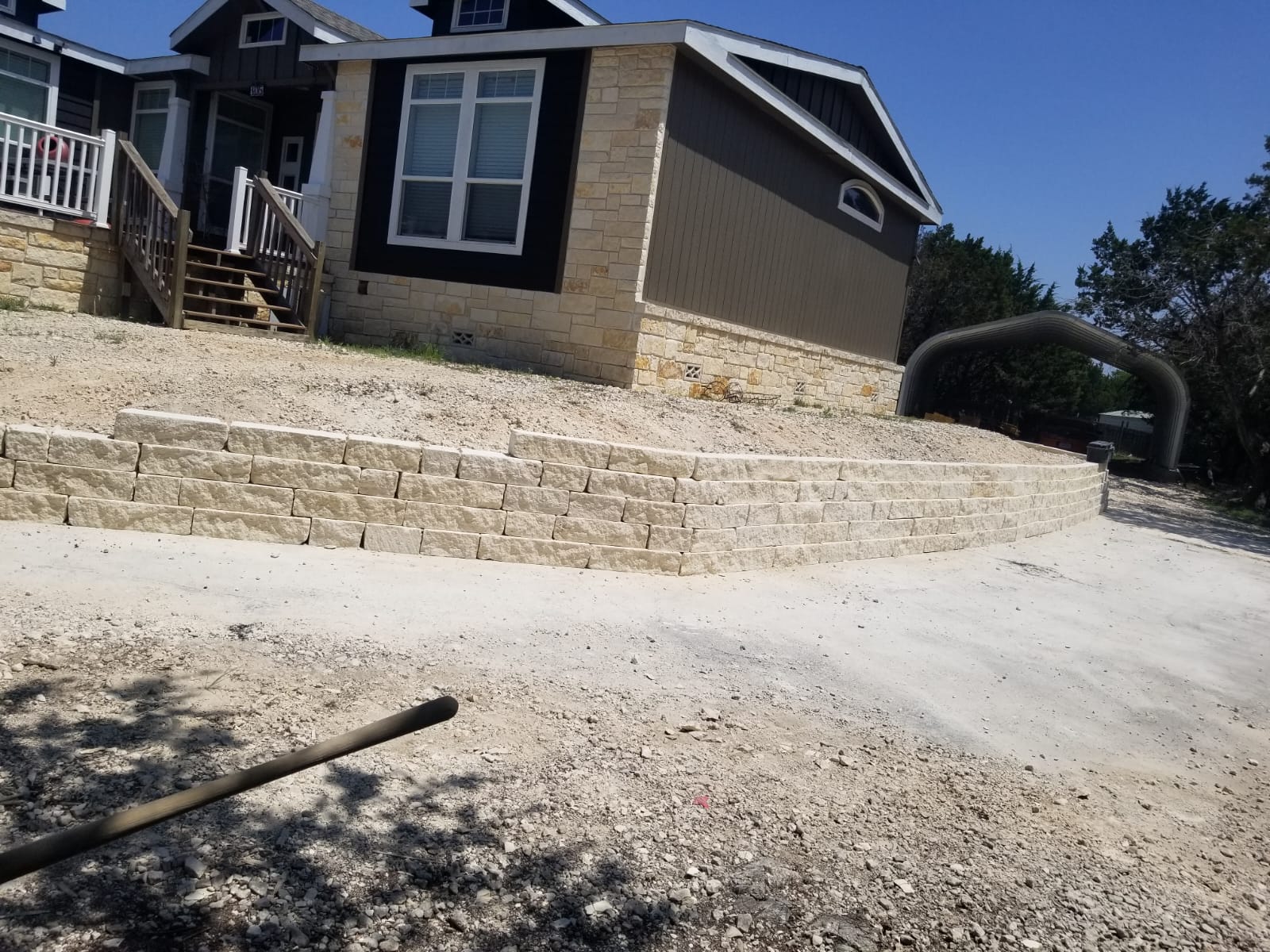 Long light-colored retaining wall supporting a sloped front yard
