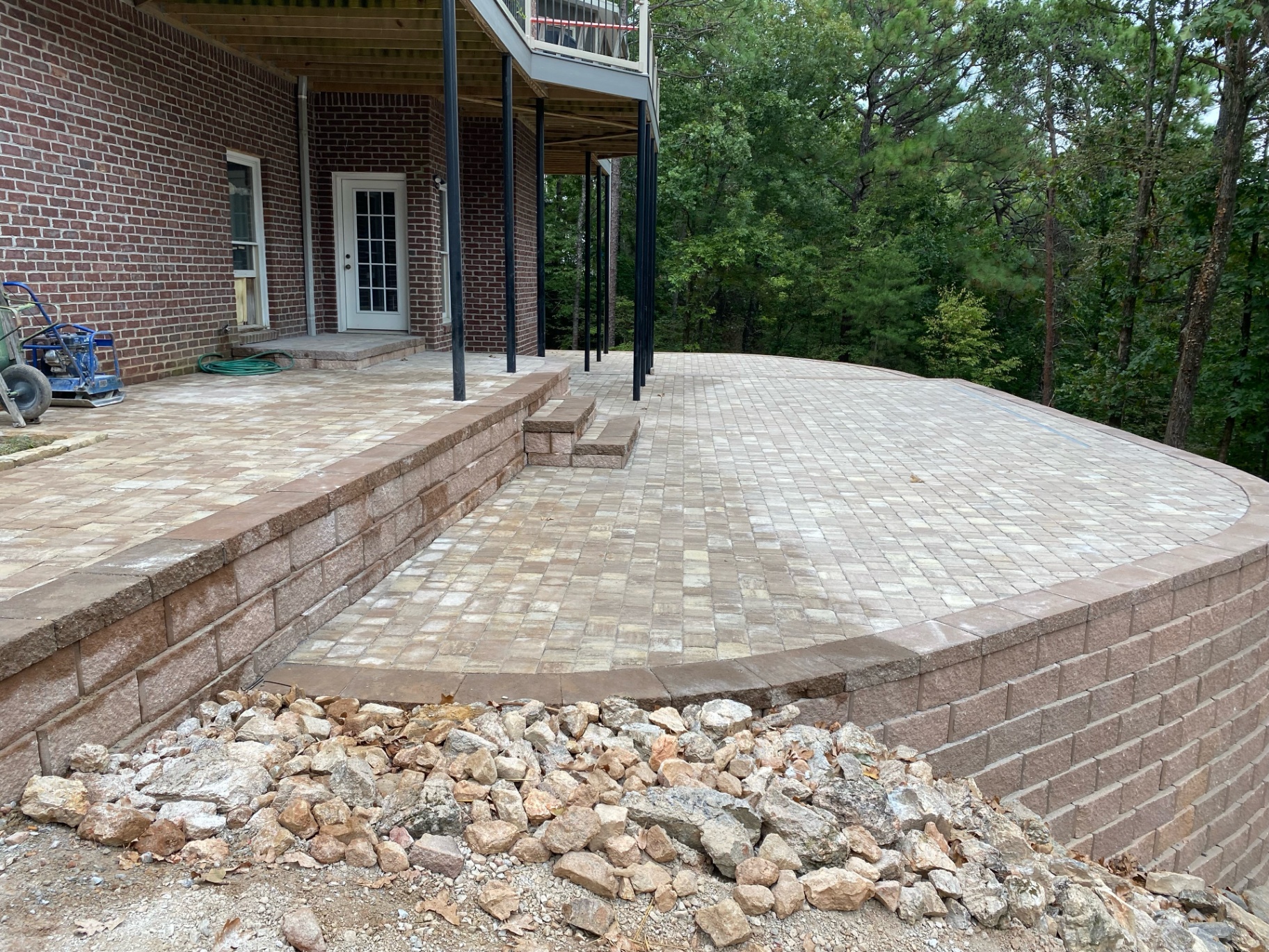 Retaining wall and paver patio installed beneath a brick home deck