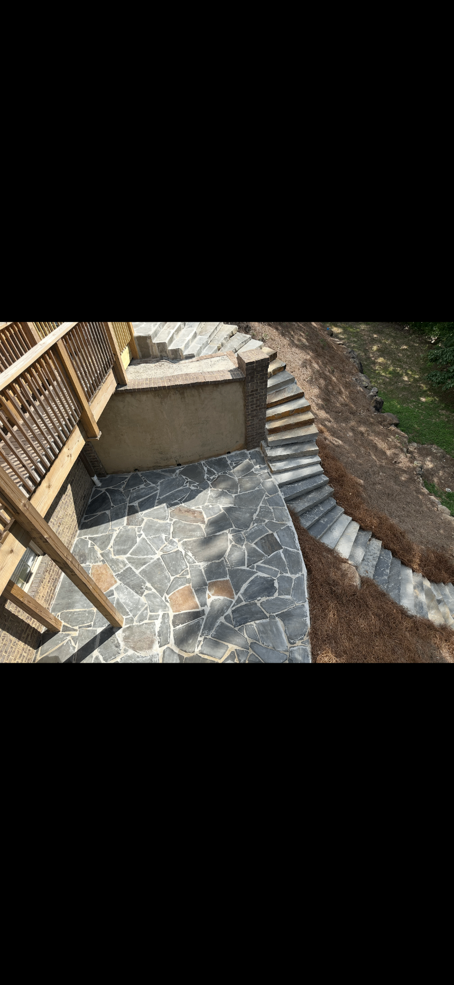 Flagstone patio with long retaining wall stairs running down a hillside
